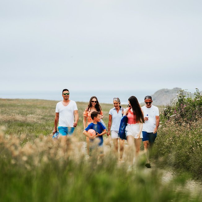 
                A family enjoying a peaceful stroll to the Cornish coastline on a summers day.
                