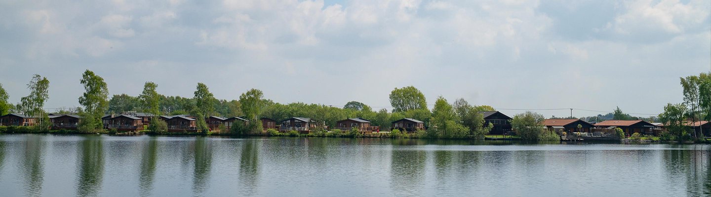 
          A panoramic view of a river with wooden lodges and trees at one of our holiday parks in Lincolnshire.
          