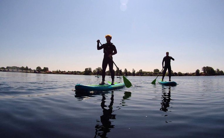 A photo of two people paddle boarding in the calm lake at our Tattershall Lakes holiday park.