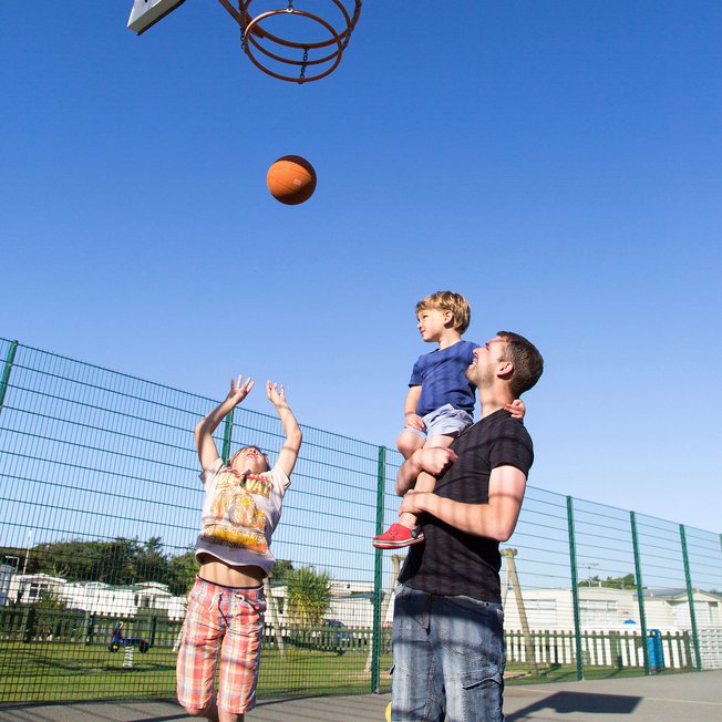 
                A family enjoying the outdoor sports court at our stunning park in North Wales, Barmouth Bay.
                