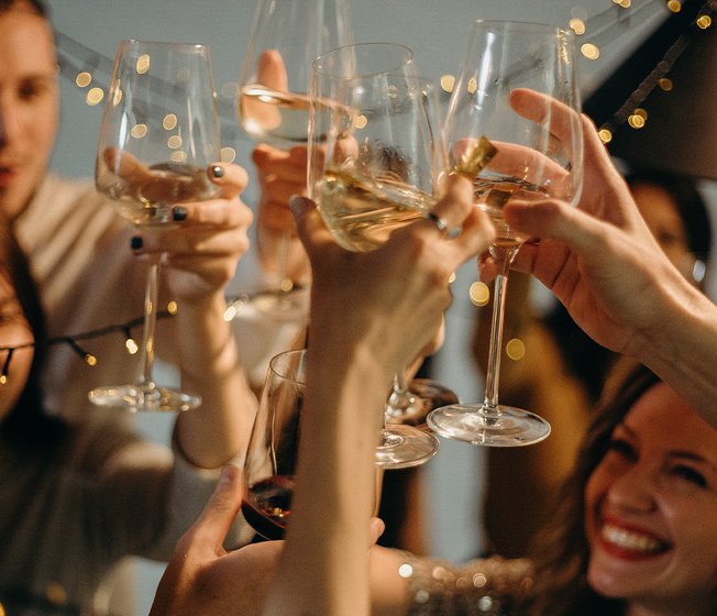 A group of people cheersing with glasses of wine.