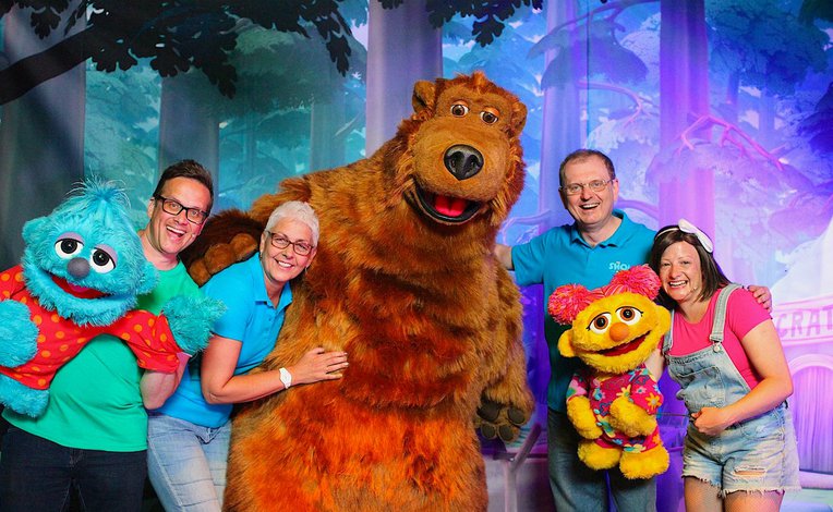 A group of people posing for a photo with the Away Resorts characters, Bear, Scratch and Lucy.