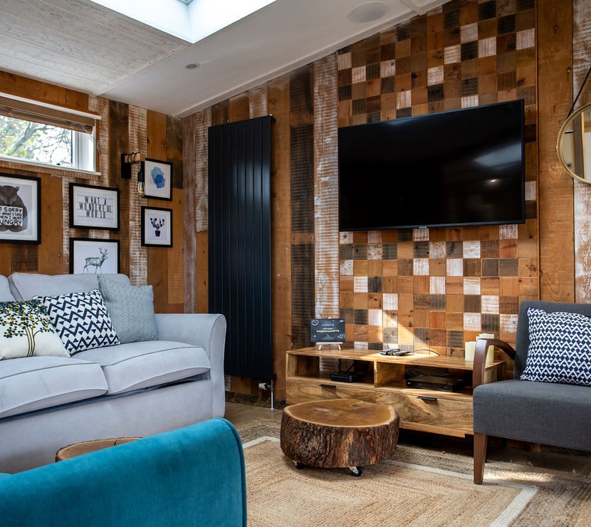 The lounge area in The Knightwood holiday lodge. This lodge has large sofas, a flatscreen TV, and plenty of rustic, woodland décor to enjoy.