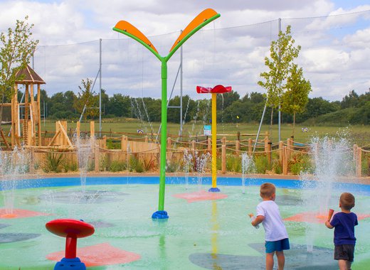 Two children playing in the outdoor splash pad at Appletree Holiday Park.
