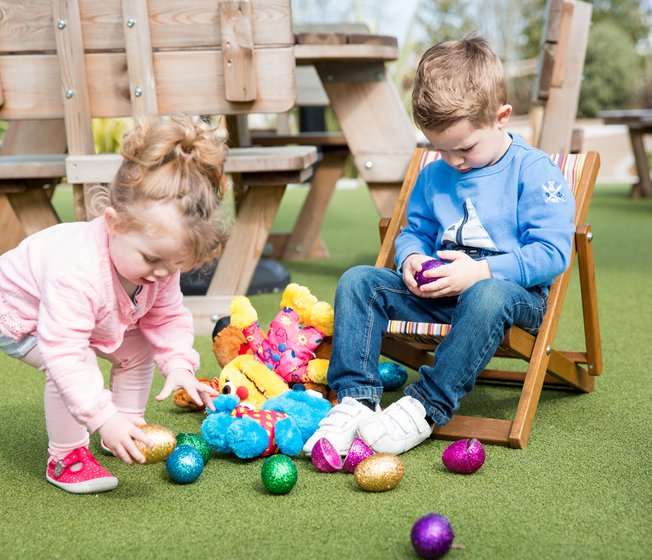 Two kids enjoying Easter activities at one of our holiday parks. They are both sitting down playing with colourful Easter eggs on the floor.