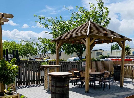 A sunny day with a view of a wooden gazebo covering a set of table and chairs at our holiday park in CLeethorpes Pearl, Lincolnshire.