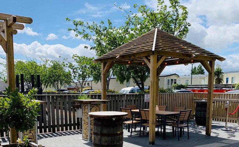 A sunny day with a view of a wooden gazebo covering a set of table and chairs at our holiday park in CLeethorpes Pearl, Lincolnshire.