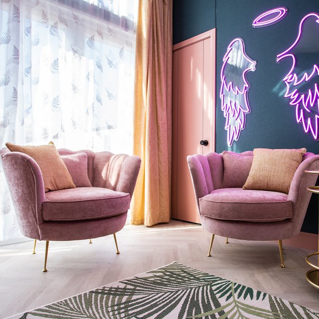 
                The instagrammable lounge area in the Esme. Sporting two pink plush velvet seats, neon lighting and a gold drinks trolley. The perfect way to stay!
                