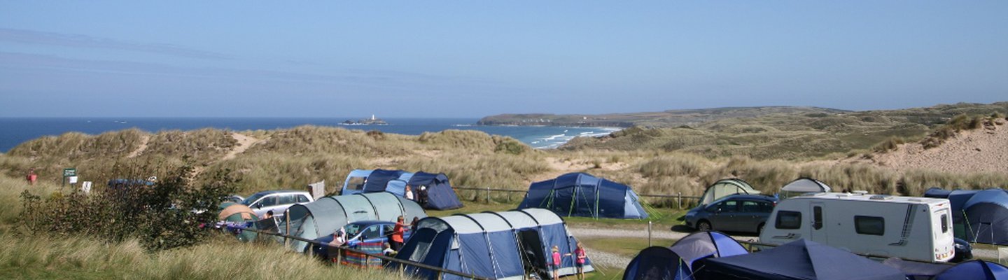 
          A view of the camping and touring pitches at St Ives Bay. There is views of the sea in the background.
          