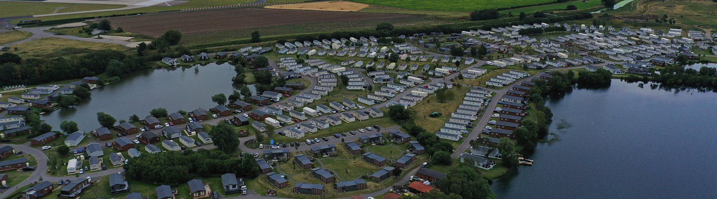 
          An arieal photo of our holiday park at Tattershall Lakes, Lincolnshire. The park has lodges and static caravans next to a large river with large fields behind it.
          