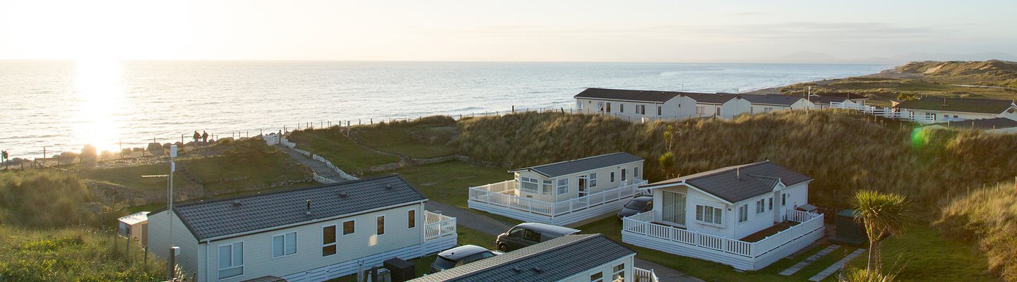 
          Two rows of caravans with views of the sea and the sun setting at our holiday park in North Wales, Barmouth Bay.
          