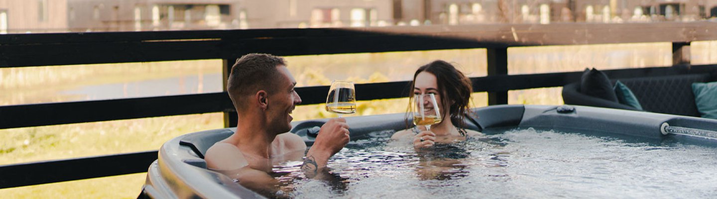 
          A couple in the hot tub at our stunning Cornish park, Retallack Resort. The male and female are enjoying a glass of wine together.
          