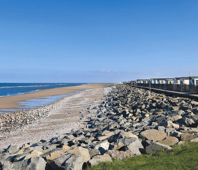 Our Golden Sands holiday park. The long beach stretches far into the distance, with rocks running along one side, and the sea on the other.