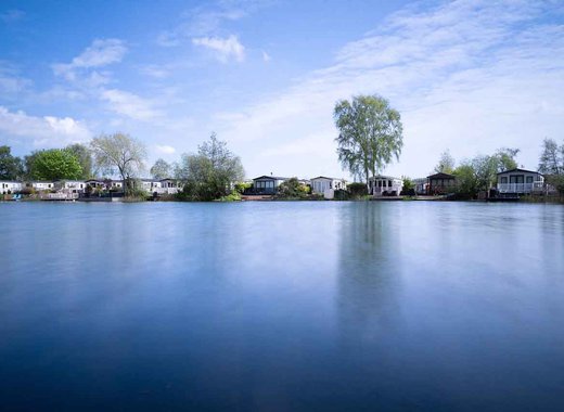 A photo of a riverside horizon during dawn of a row of static caravans.
