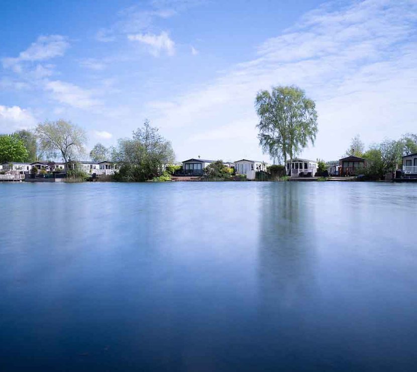 A photo of a riverside horizon during dawn of a row of static caravans.