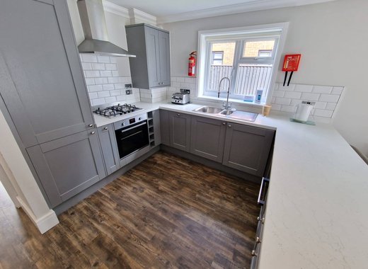 A kitchen within one of our cottages. A U shaped kitchen with clear and clean counter space. Modern grey cabinets and a window above the sink.