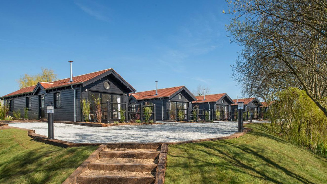 
              A row of holiday homes at The Lakes Rookley, Isle of Wight, on a sunny day. Explore our stunning accommodation options.
              