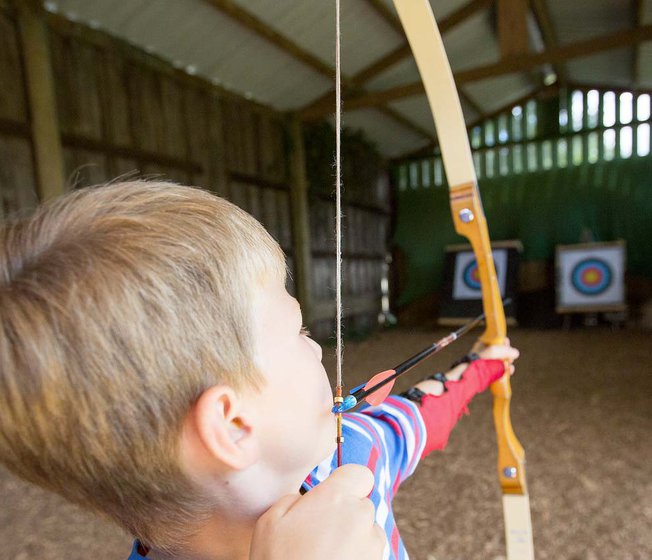 A young boy enjoying our on-site activity, archery.