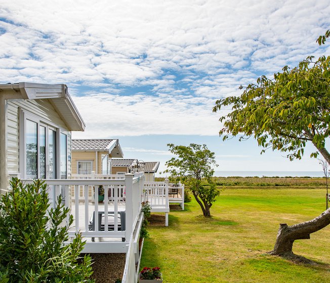 A row of caravans at our park in Essex, Mersea Island, with views of the sea in the background.