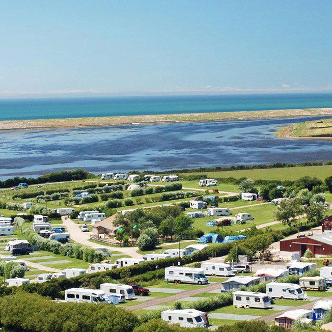 
              A bright sunny day overlooking our East Fleet Farm holiday park in Dorset. There are vast areas of countryside and a river to the horizon.
              