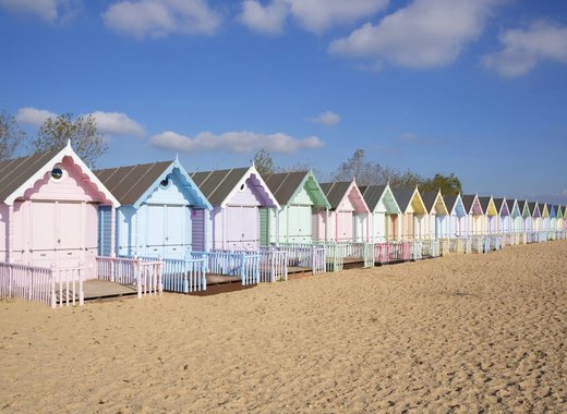 A row of multicoloured beach huts on the beach.