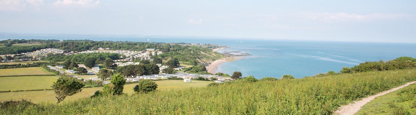 
          A panoramic shot taken up on a hill looking out at our holiday park and the sea on a sunny day.
          