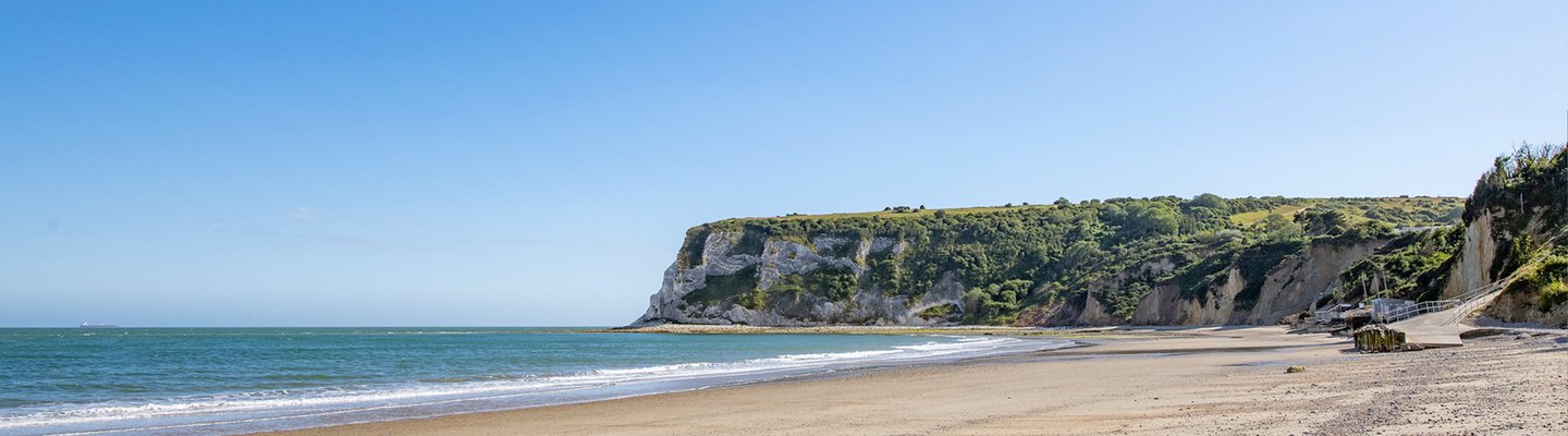 
          A bright and sunny day at a coastal cliff beach.
          