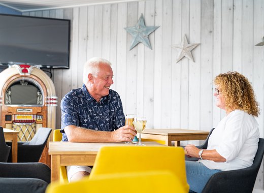 A couple enjoying a drink together at The Muddy Duck Clubhouse at our Essex holiday park, Mersea Island.