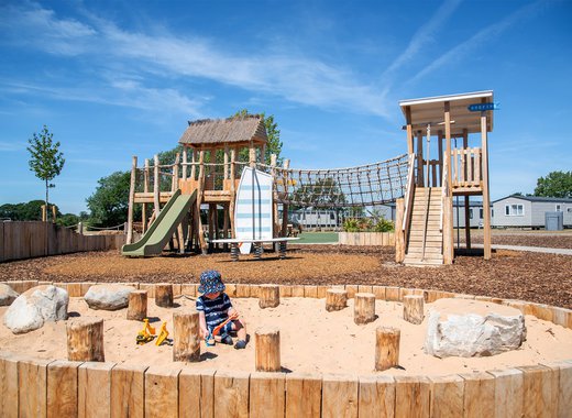 Child playing in the sand at our adventure playground in the sunshine at Mill Rythe Holiday Park, Hampshire.