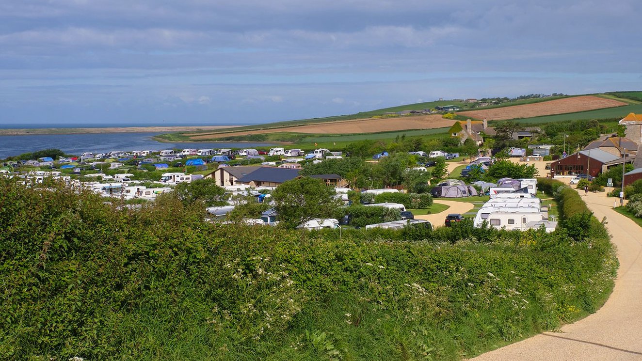 
              Mobile caravans parked with a wide angle view of the vast countryside and the lagoon located at our East Fleet Farm holiday park in Dorset.
              