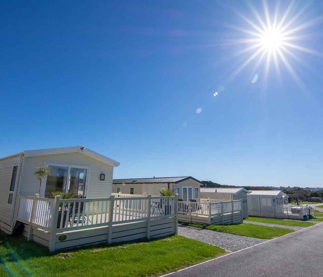 Holiday caravans line down the road, with a big blue sky above and the sun shining brightly.