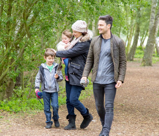 Family of four walking through trees together at Tattershall Lakes.
