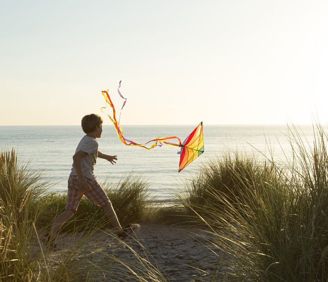A child flying a kite at sunset over our stunning North Wales holiday park, Barmouth Bay.