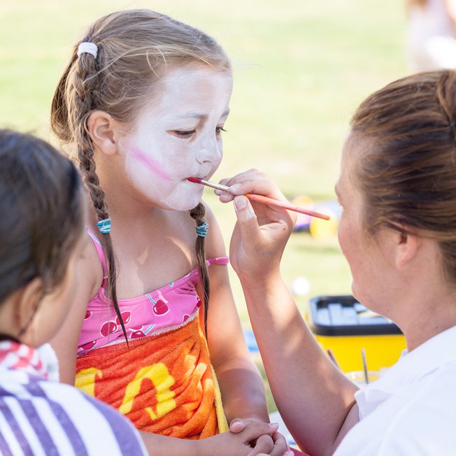 
                A child getting their face painted.
                