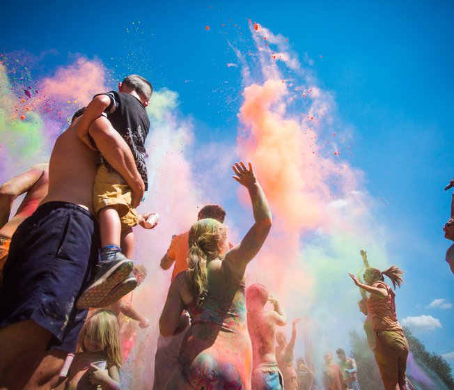 A young family enjoying the colour dash festival on a bright sunny day. We offer this and many more fun events at our Whitecliff Bay holiday park.