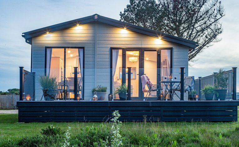 A photo of a static caravan with the patio doors facing the camrea. The photo is taken durng a sunset.