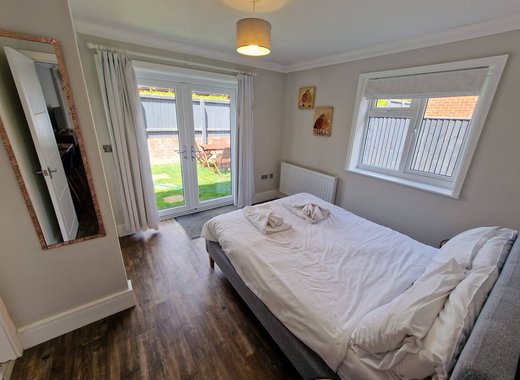 A double bedroom in one of the rooms within our cottages. opposite the double bed are french doors that lead to a garden area. To the right of the bed is a window, also looking out to the garden area.