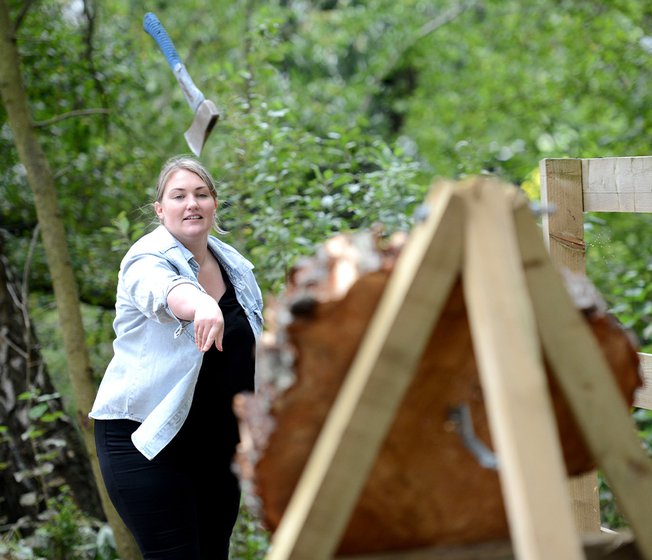 A lady taking part in the target axe throwing activity.