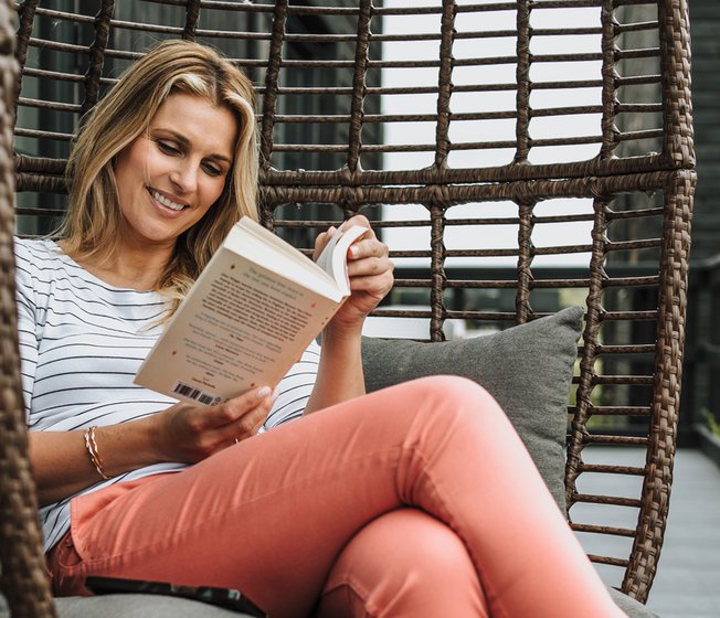 Smiling lady enjoying her book at one of our parks.