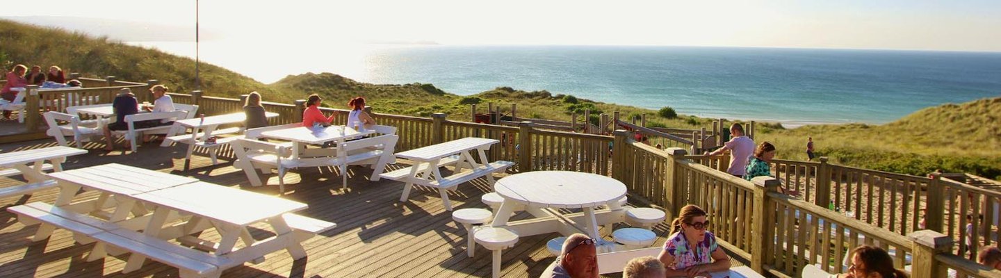 
          The outdoor eating area of our restaurant at St Ives Bay Holiday Park, with views of the sea.
          