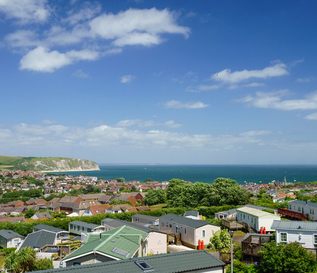 Our holiday park, Swanage Bay View. The bright, sunny day is showing the many holiday homes in the park, along with a view of Dorset, the sea, and the cliffs.