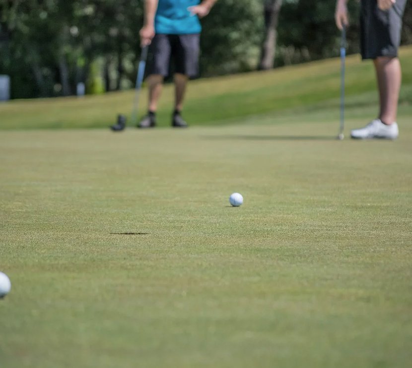 A close up image of two tennis balls at Playgolf Colchester. There are two people standing in the background.