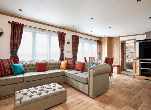 The Heartwood holiday home lounge area. This space has a large sofa, a dining area, and décor that reflects Scottish baronial living.
