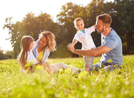 A young family playing in the grass outside on a sunny day.