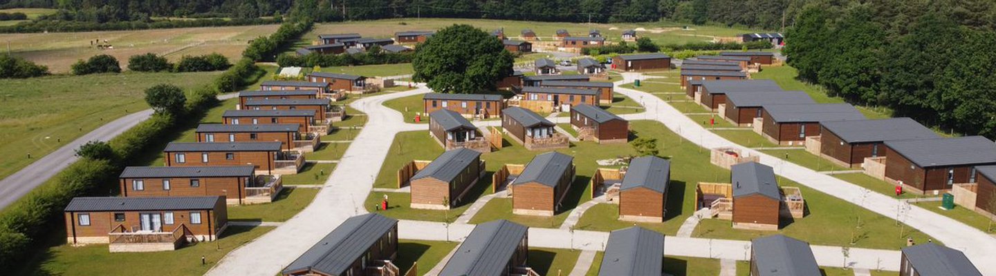 
          Drone footage above our stunning resort Clumber Park, Nottinghamshire. There are rows of wooden holiday homes perched within stunning woodland scenery.
          